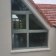Ensemble de fenêtres en mélèze triple vitrage sous un pignon triangulaire, vue extérieure