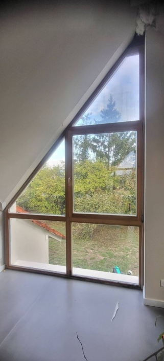 Châssis fixes et ouvrant en mélèze suivant la pente du toit, vus de l'intérieur
