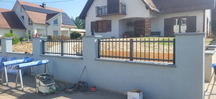Pose des éléments de clôture en aluminium anthracite sur muret enduit