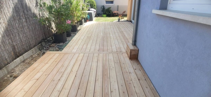 réalisation d’une terrasse en mélèze du Canada avec fixation invisible Vue d'ensemble des lames de mélèze du Canada fraîchement posées le long de la maison