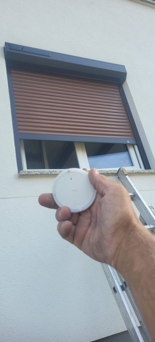 Volet roulant solaire Somfy à lames teinte bois et sa commande radio io, posé par HRV Menuiserie (Betschdorf)